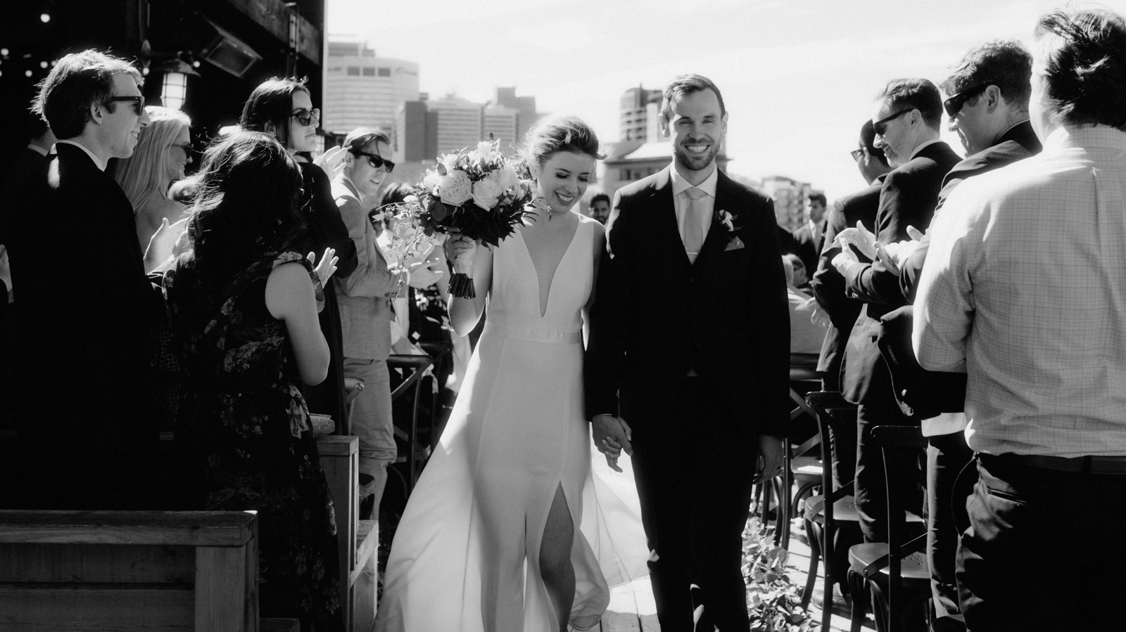 Couple celebrating during their recessional during their windy rooftop Charbar ceremony