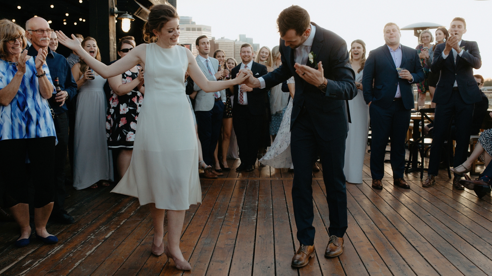 Couple bowing to their guests after their rooftop first dance at Charbar in Calgary