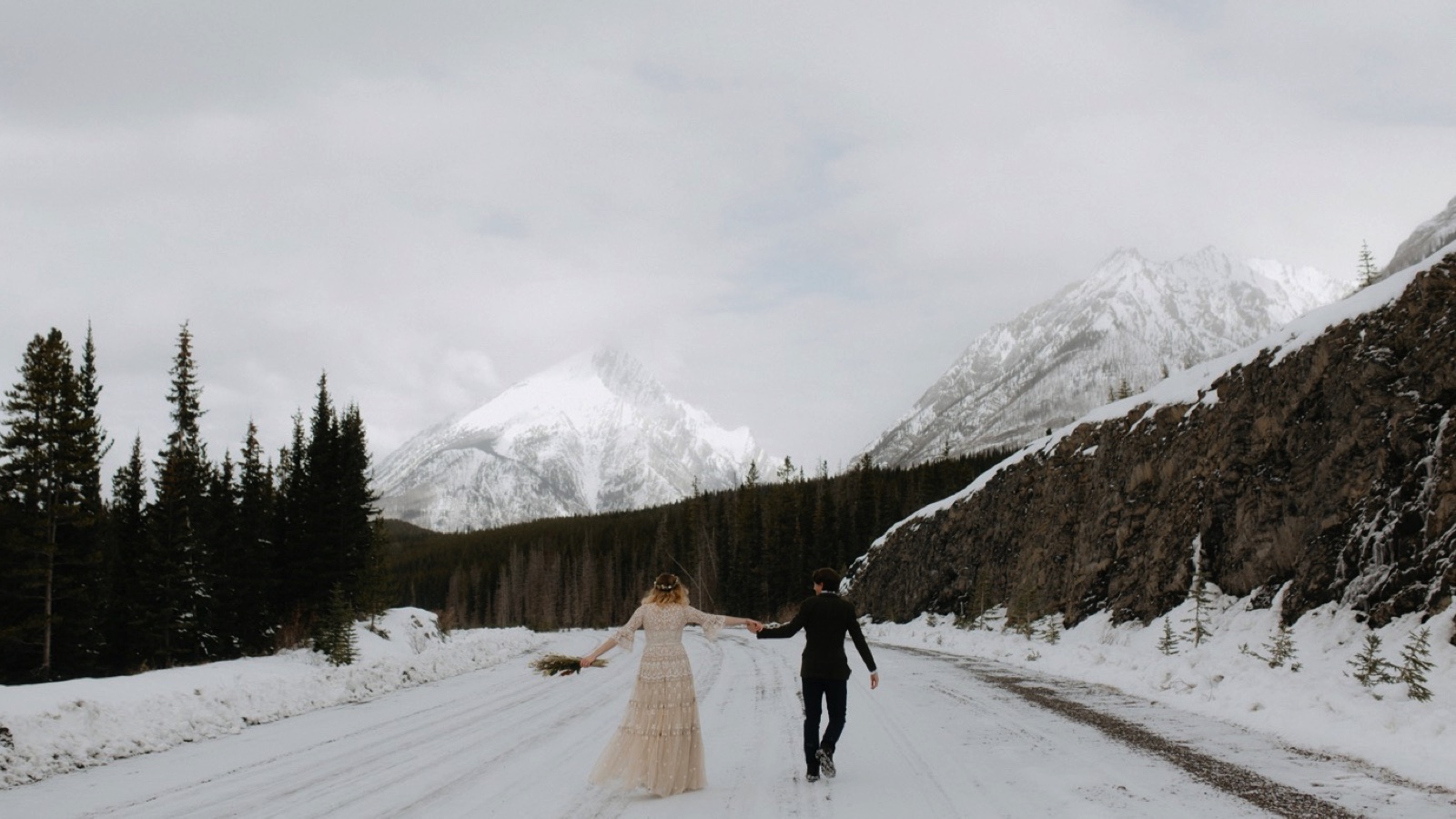 Couple walking along the frozen Spray Lakes road after their elopement in Kananaskis