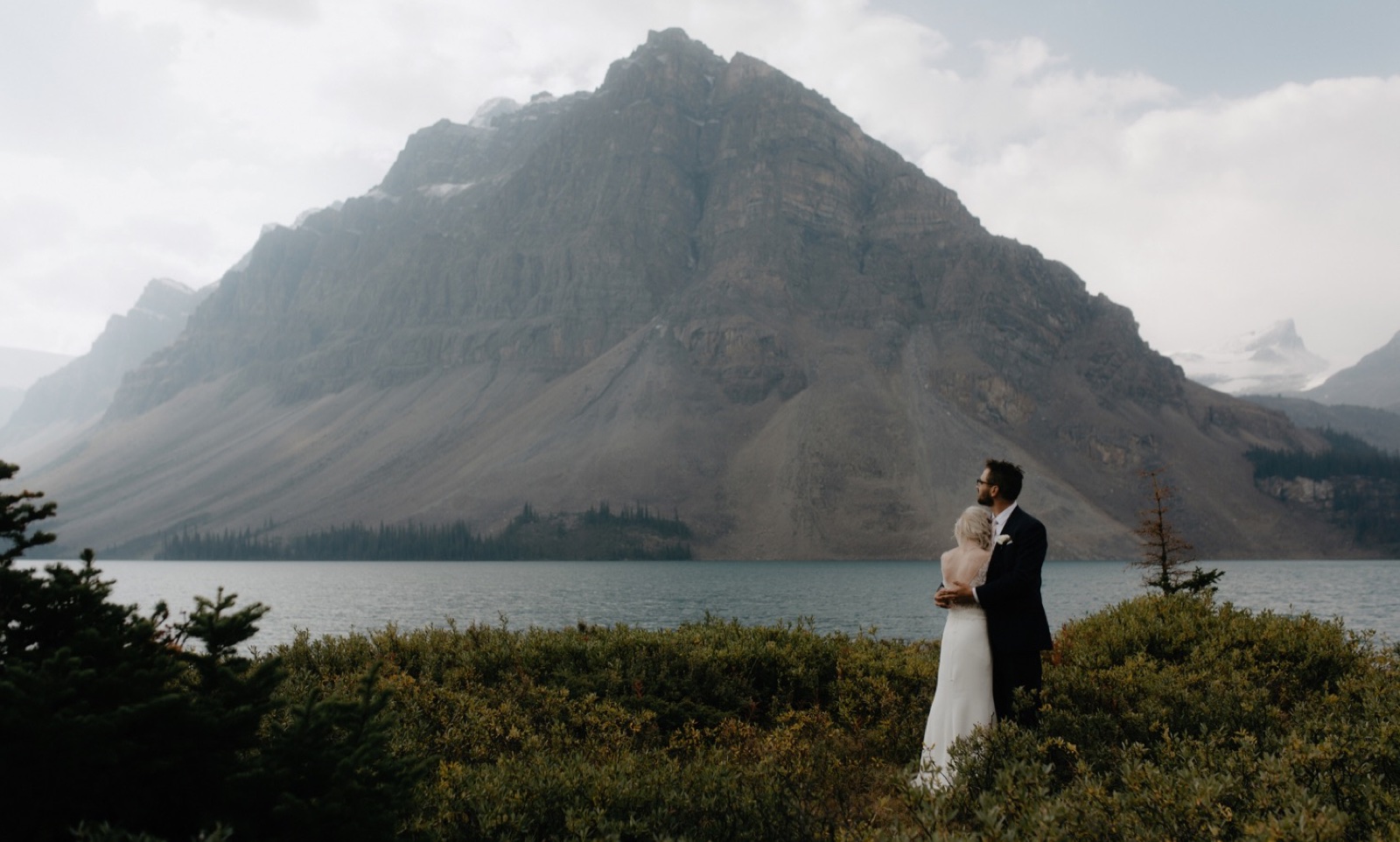 Couple hugging in the shrubbery filled meadow overlooking lakes on the Icefield Parkway
