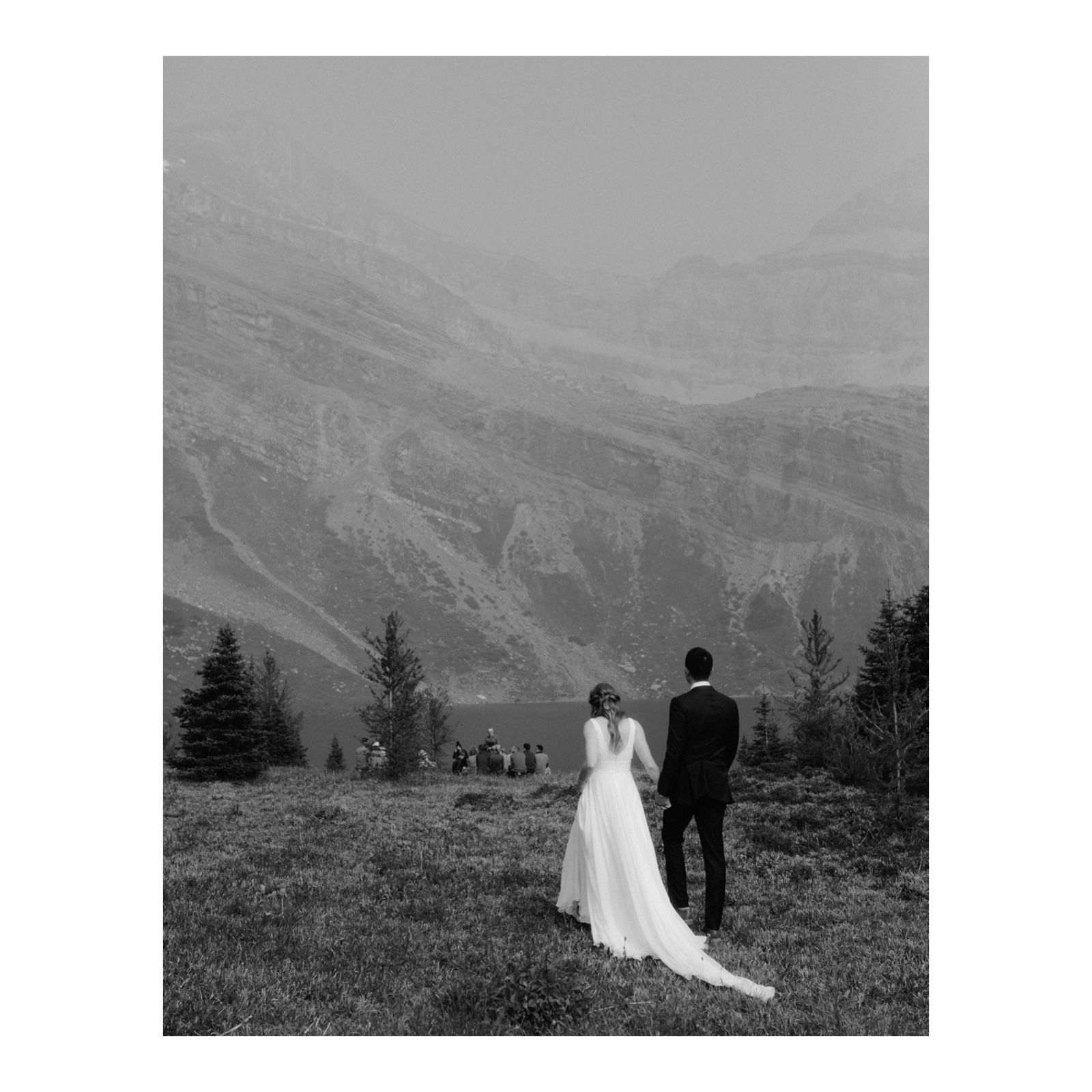 Bride and groom walking to their ceremony together on a smokey day at Hidden Lake near Skoki Lodge