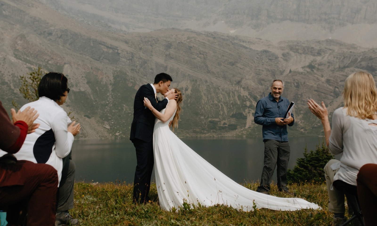 Couple epically kissing at their lakeshore wedding ceremony overlooking glacial Hidden Lake near Skoki Lodge