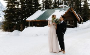 Couple walking among the historic log cabins at Storm Mountain Lodge by Banff