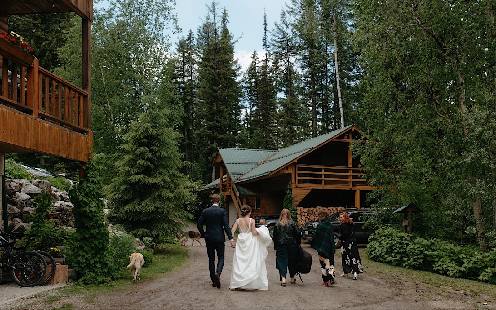 Dog-friendly bridal party walking to wedding reception amongst chalets in Golden, BC