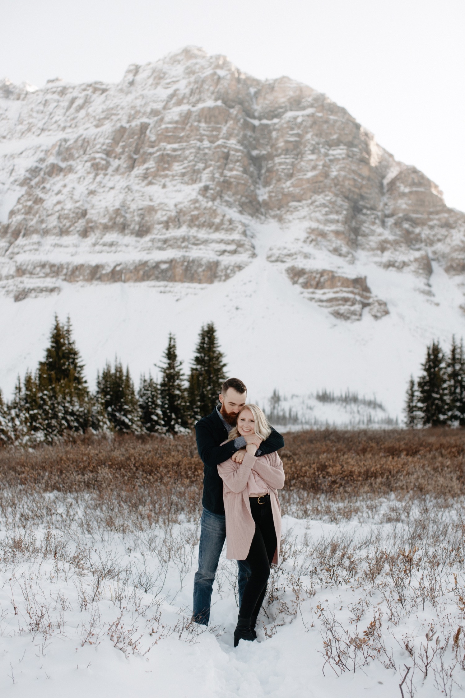 Couple in a meadow on the shores of Bow Lake in Banff National Park up the Icefields Parkway with a mountainous backdrop