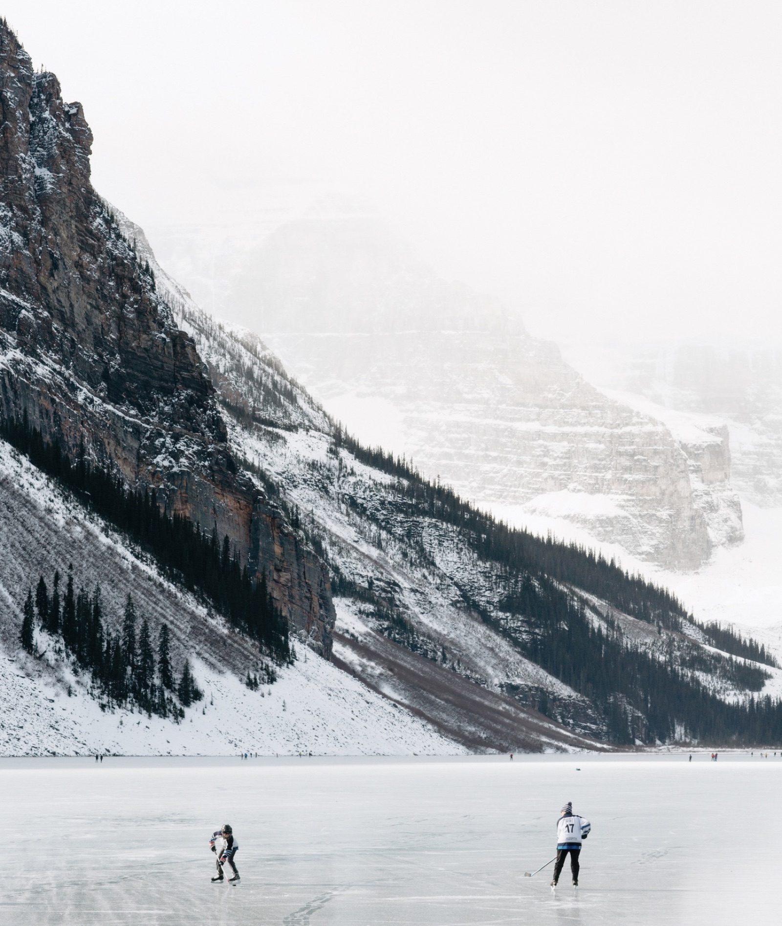 Young boy and his mother playing hockey on the frozen Lake Louise in Banff National park