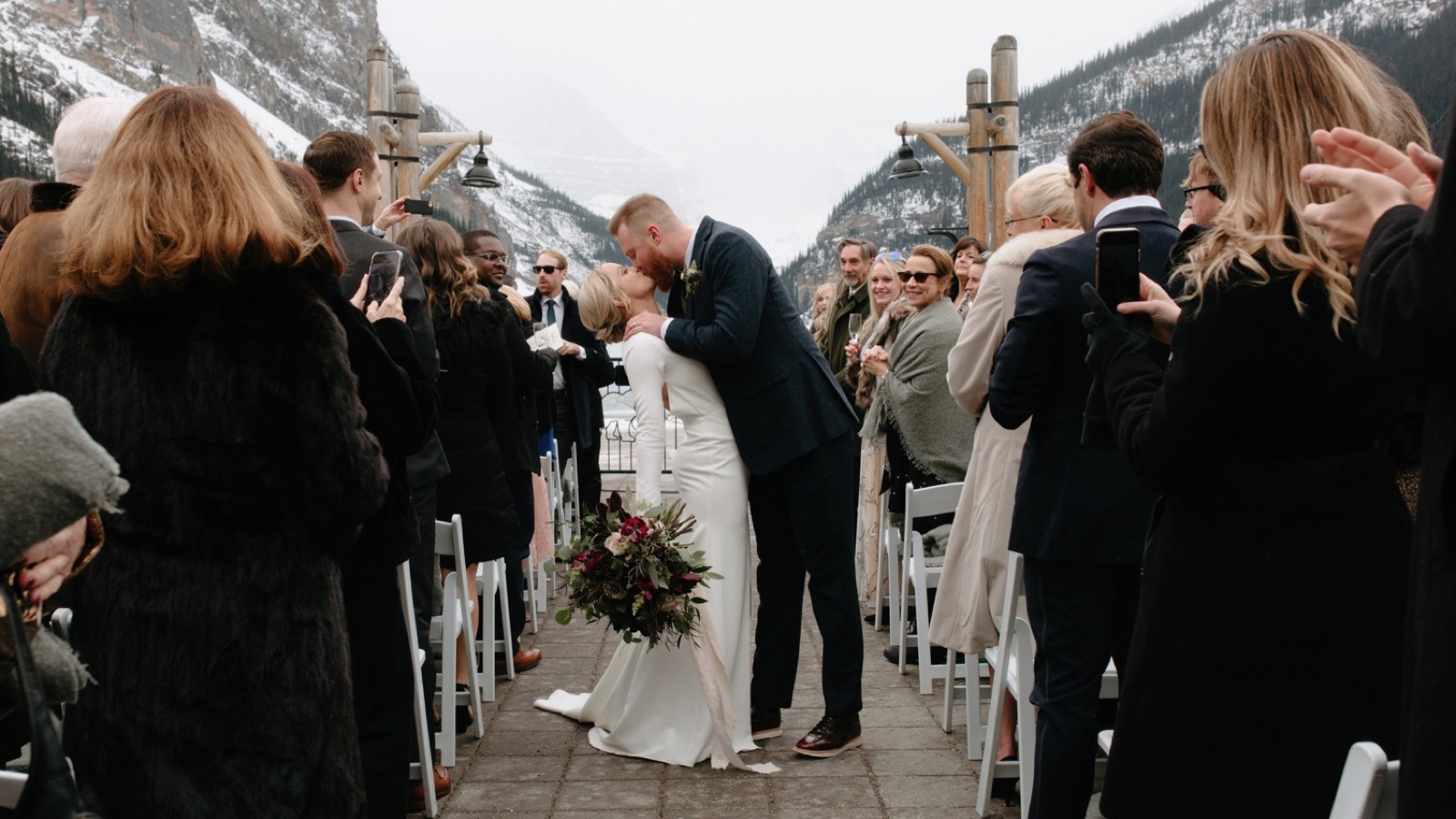 Kiss mid-aisle during a wedding couple's recessional at their outdoor winter ceremony at Lake Louise