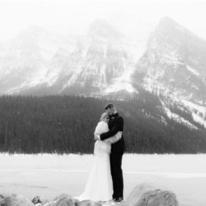 Winter wedding portraits along the recently frozen Lake Louise in Banff National Park with a bride wearing a faux fur cape