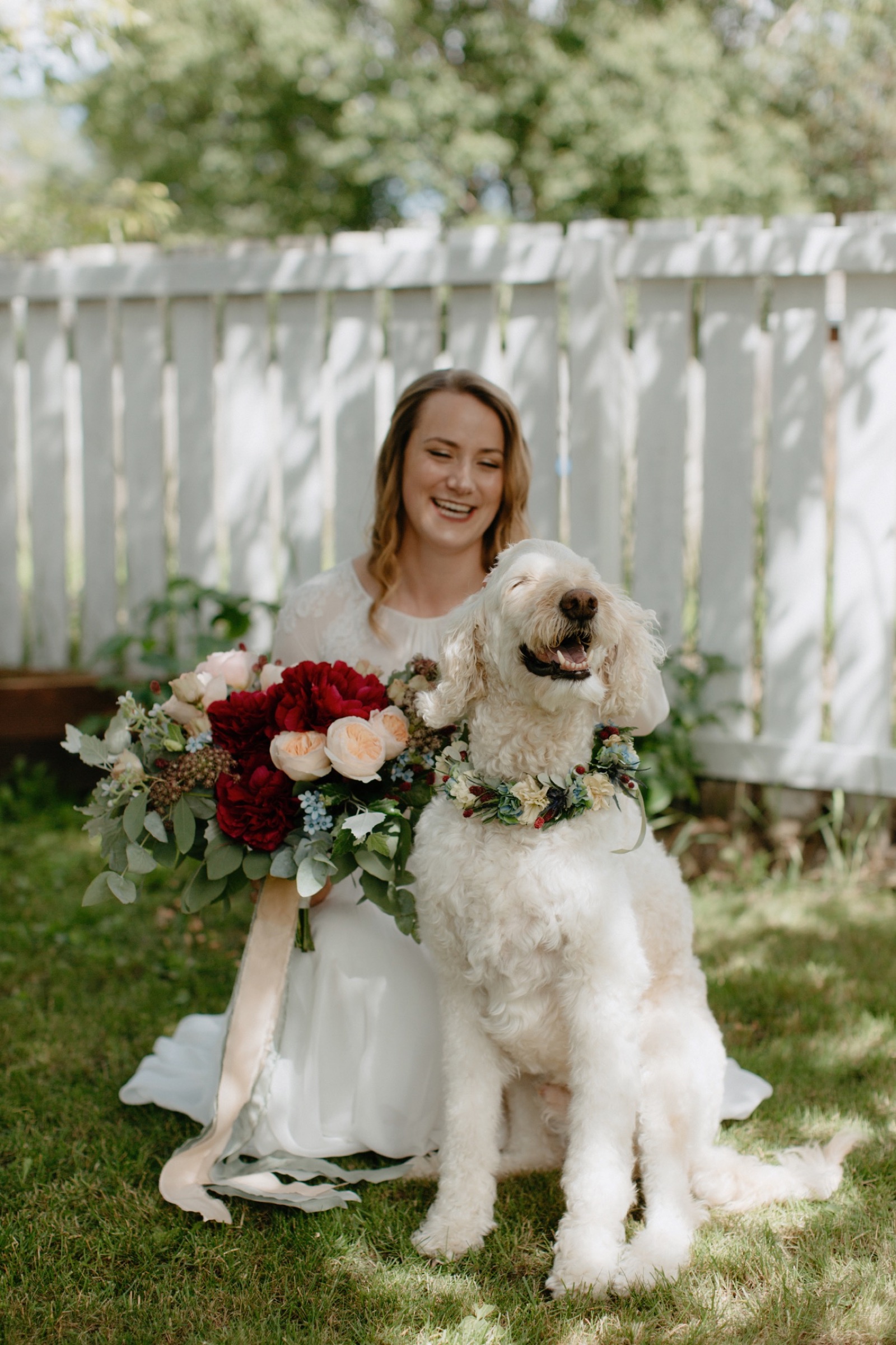 Bride and her oh so happy dog wearing a floral collar in her backyard before the ceremony