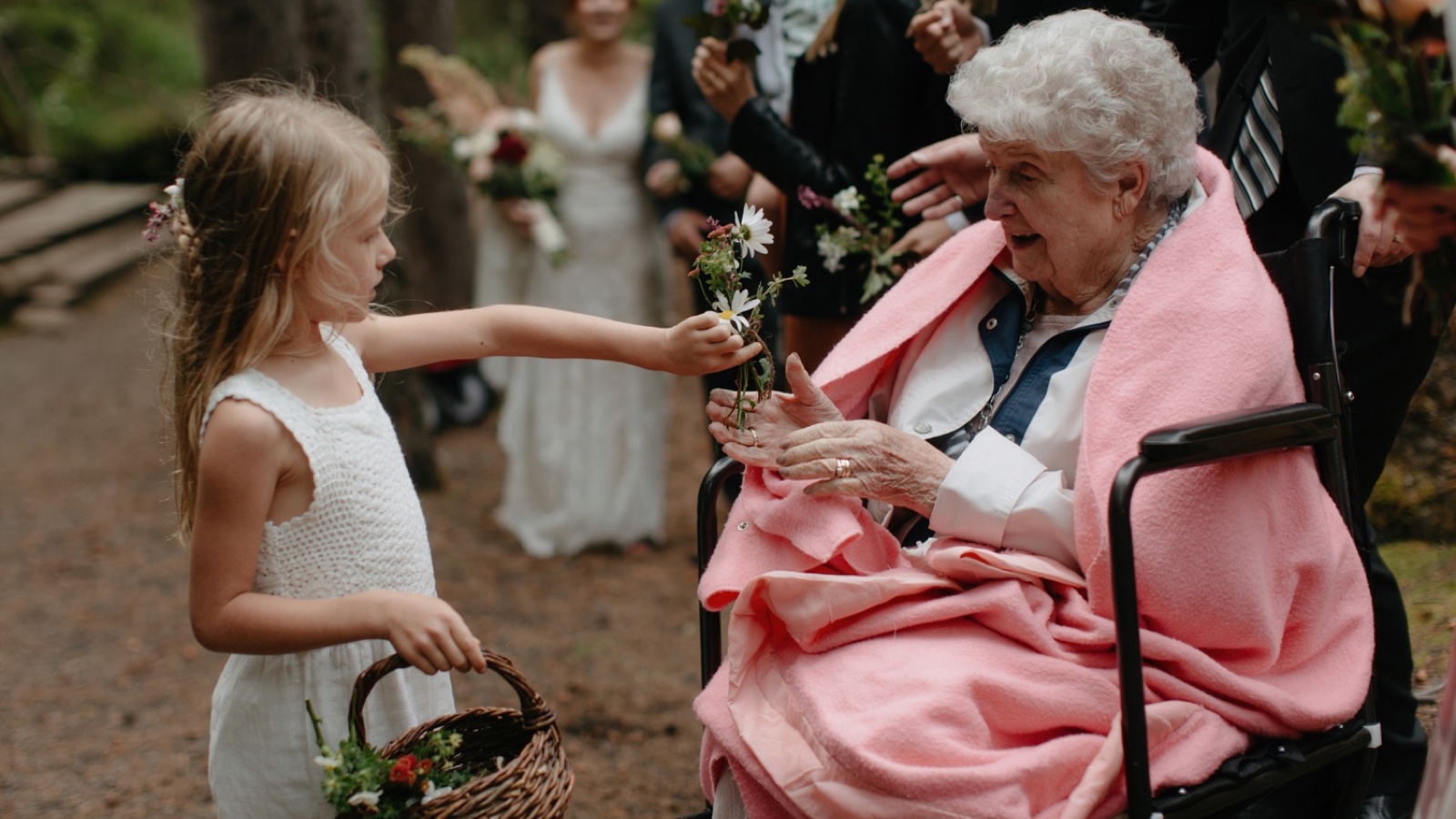 Flower girls handing small organic floral arrangements to each guest before the wedding ceremony