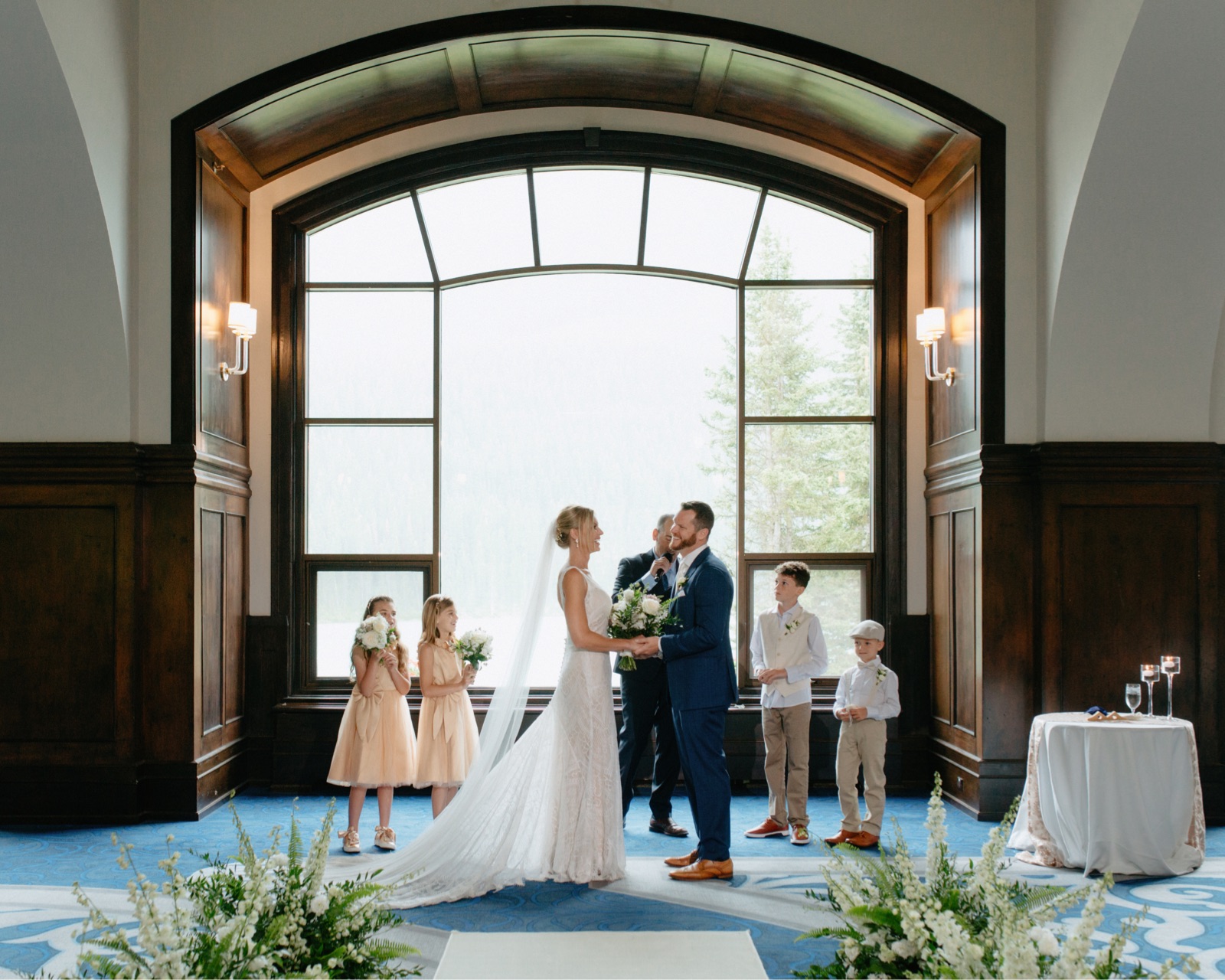 Indoor wedding ceremony in the Victoria Ballroom with window backdrop overlooking Lake Louise