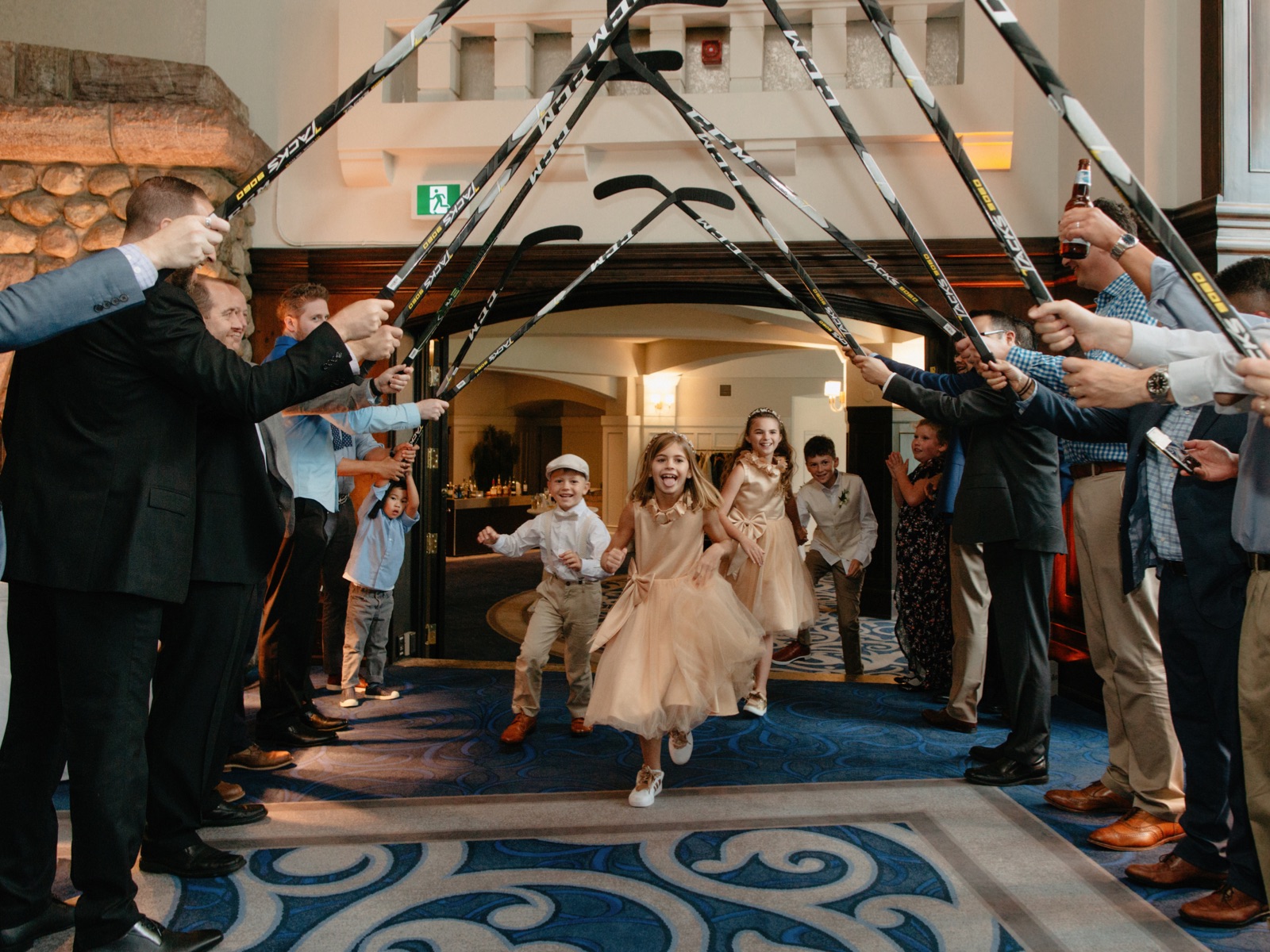 Kids' hockey stick tunnel entrance into their parents' wedding