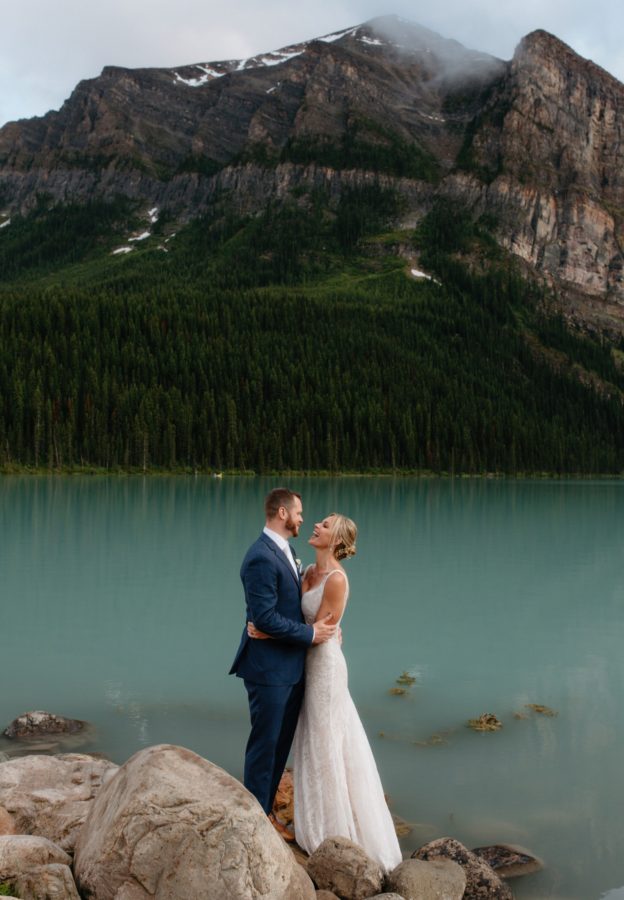 Couple's wedding portraits on the rocks by Lake Louise in July