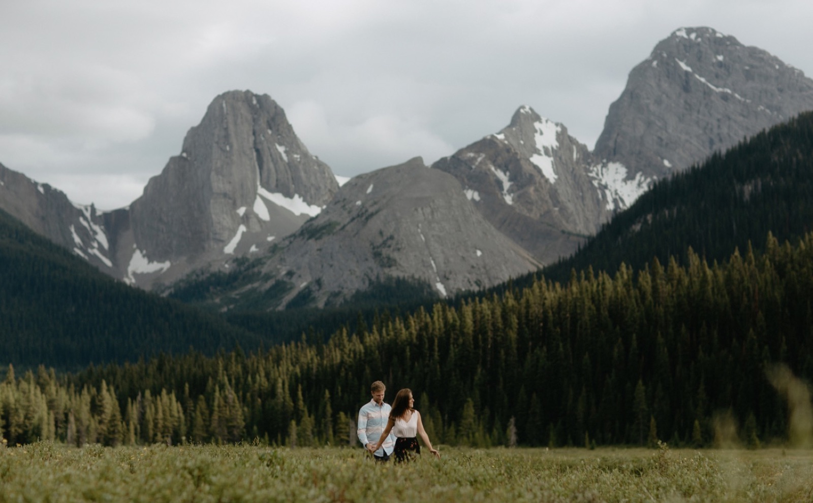 Engagement couple walking through the meadow at Engadine Lodge