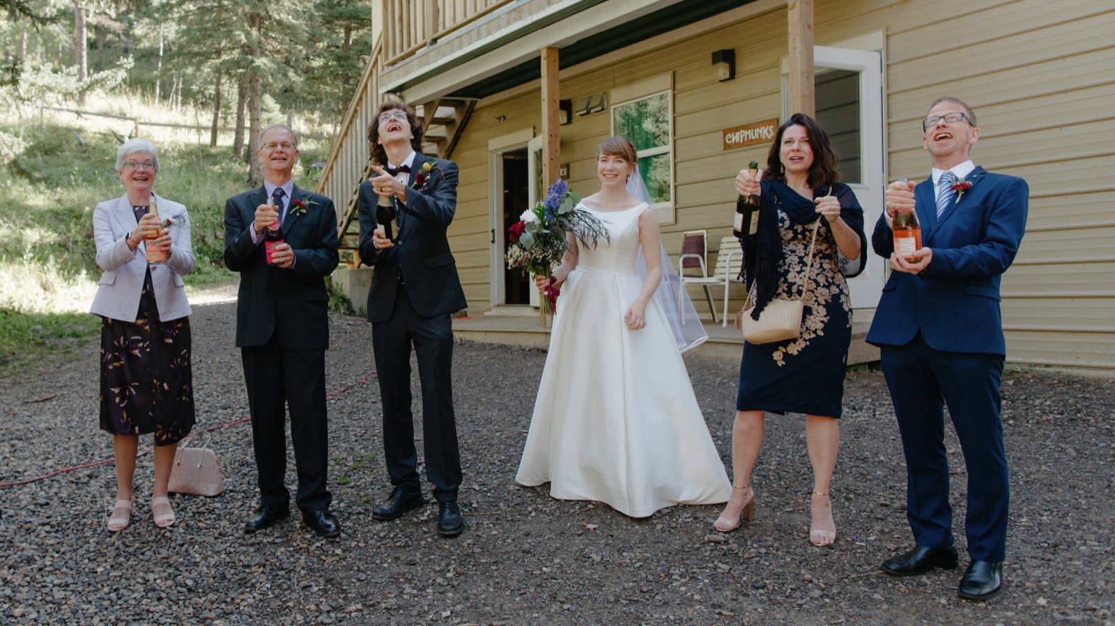 Wedding couple popping champagne with their parents during the receiving line