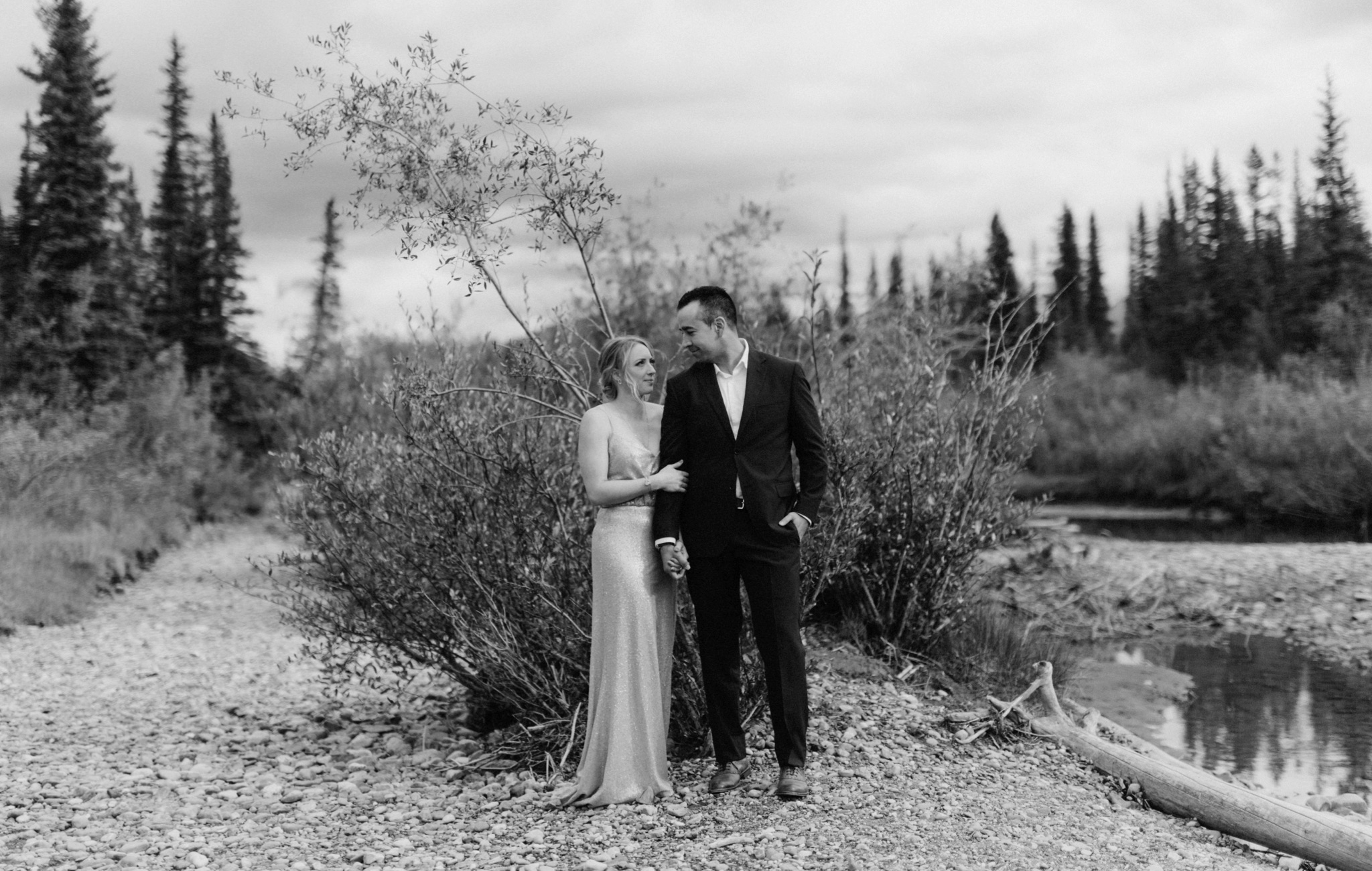 Timeless black and white wedding couple portraits beside a creek in Canmore