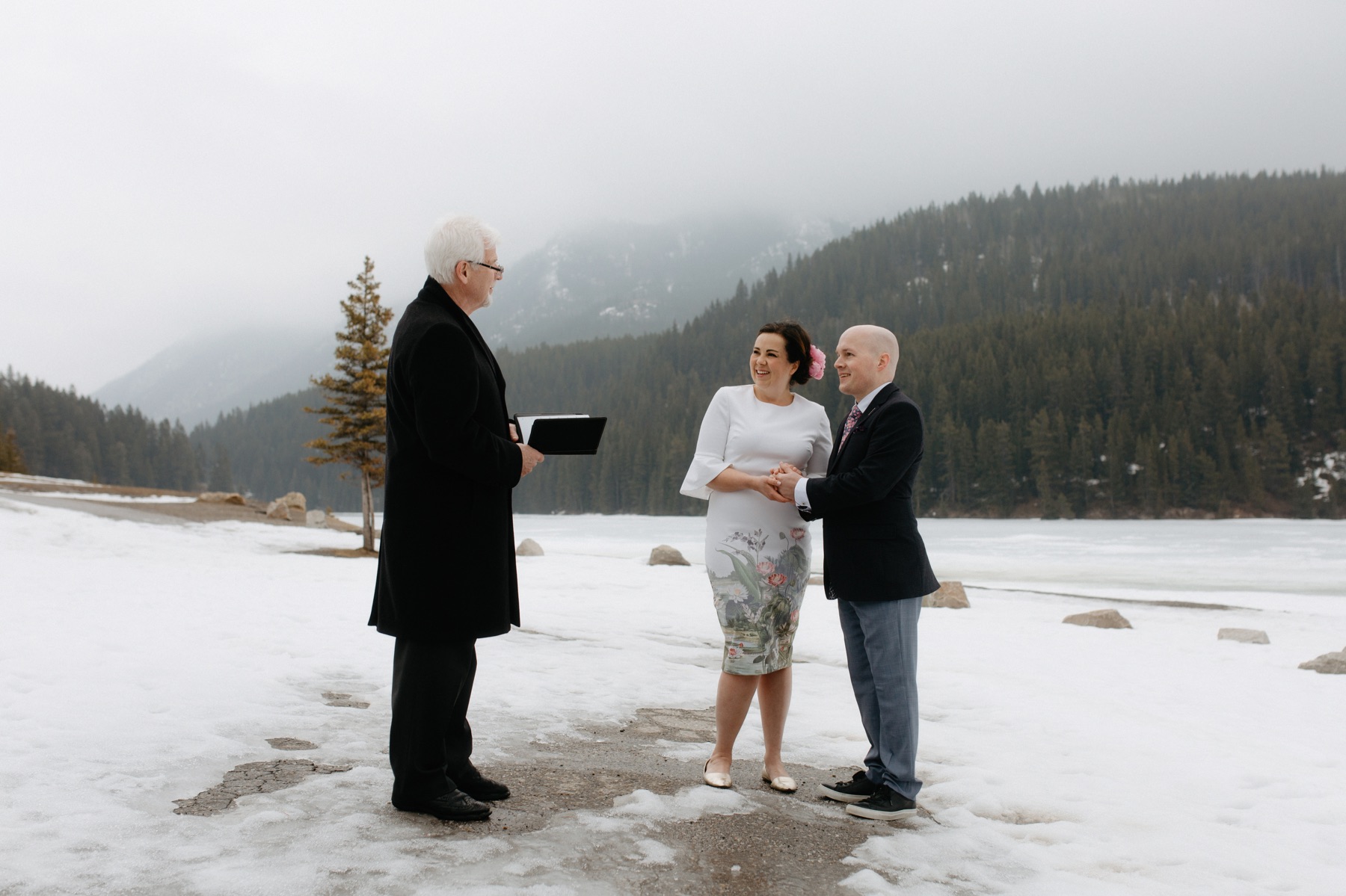 A winter ceremony with couple and officiant at Two Jack Lake in Banff National Park