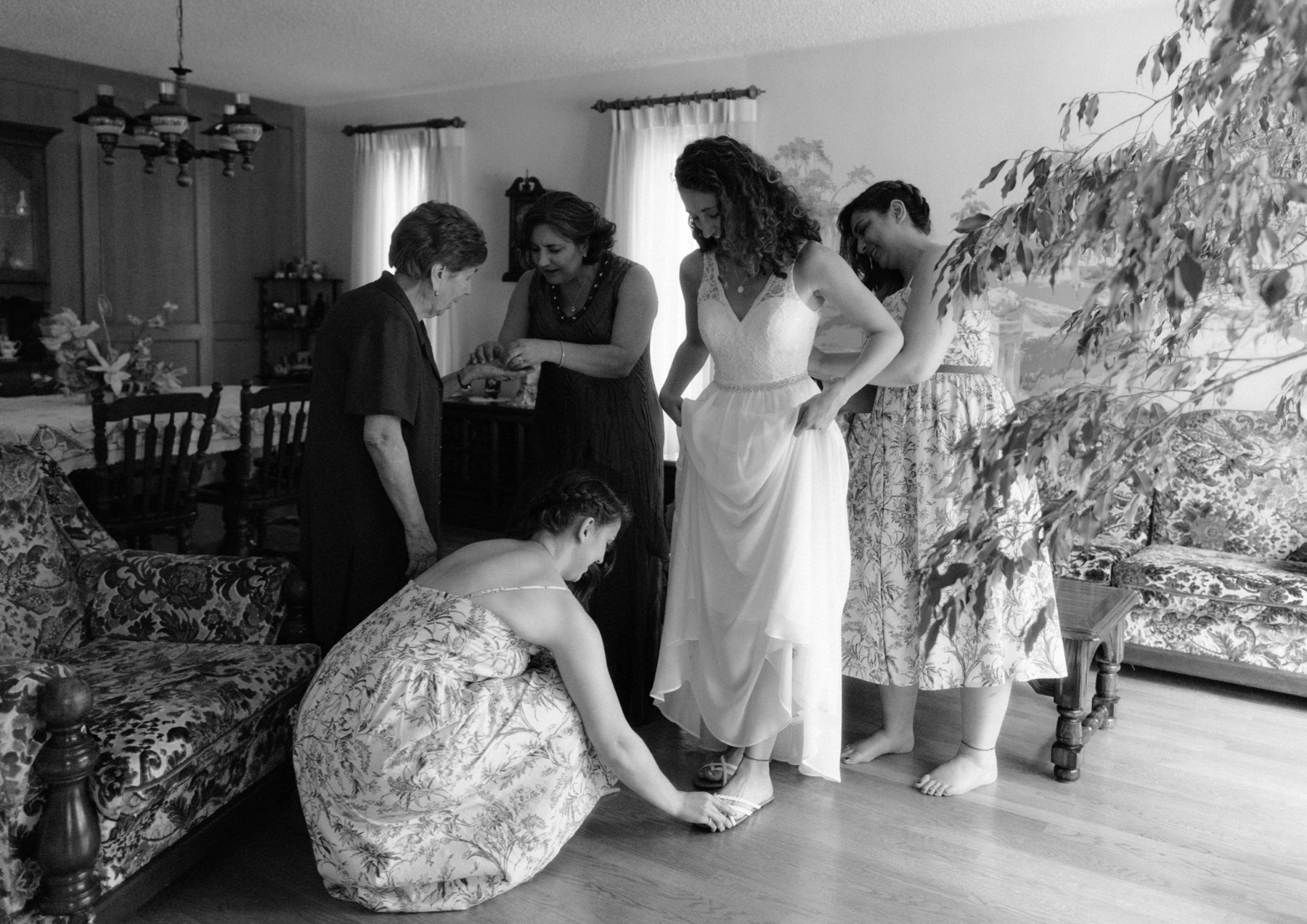 Bride getting ready with the help of her sisters, mother and grandma slipping on her shoe