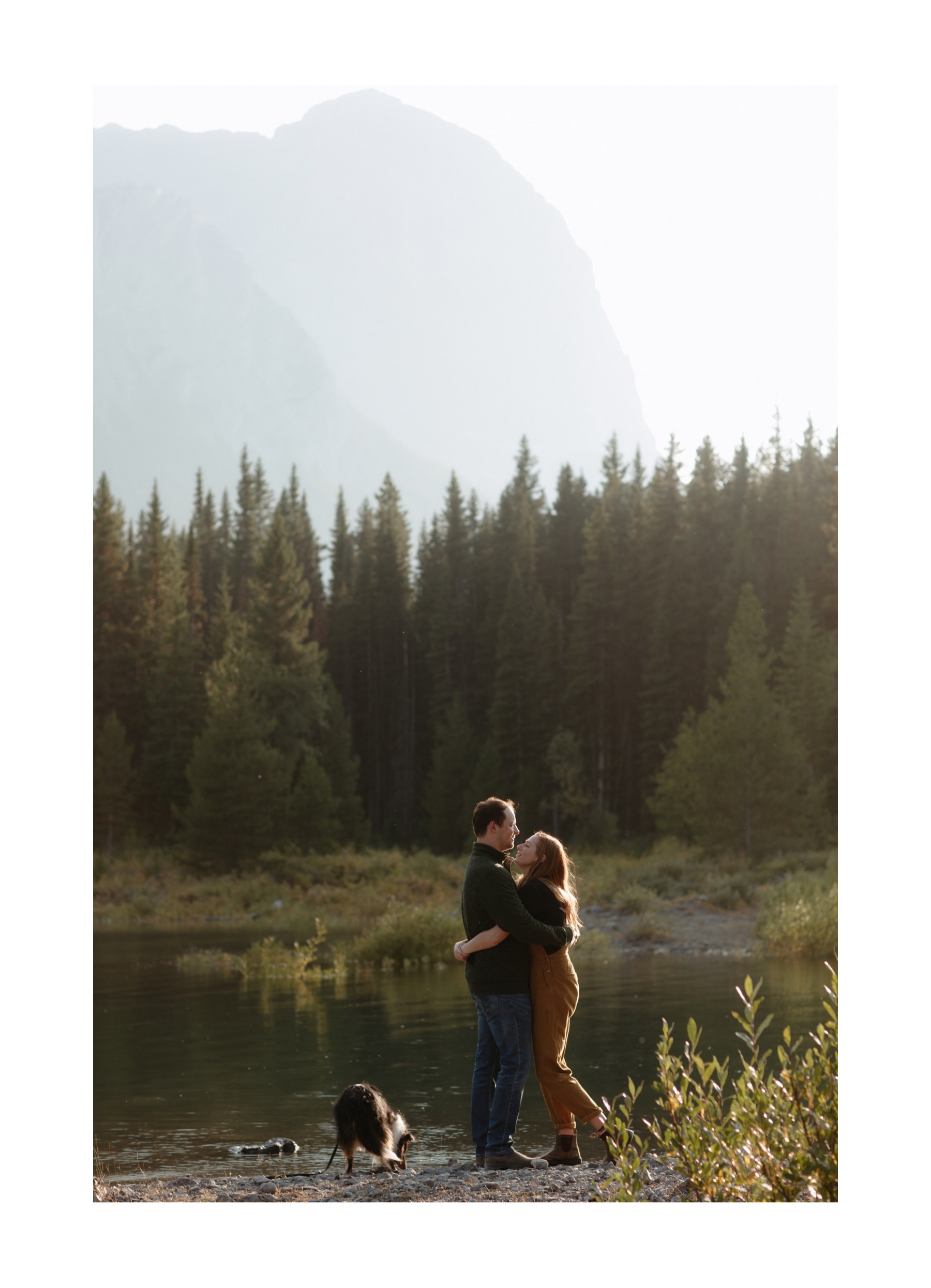 Couple embracing at Upper Kananaskis Lake with a hazy Sarrail Ridge and Rawson Lake behind them