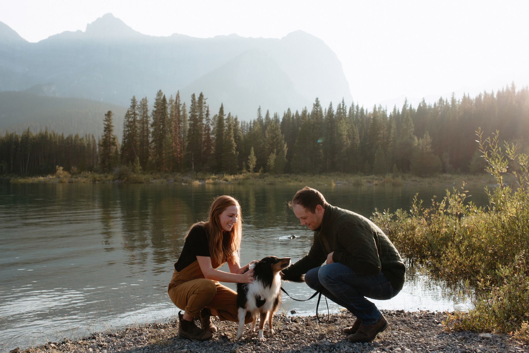 Couple playing with their dog along the lakeshore in Kananaskis during a smokey sunset