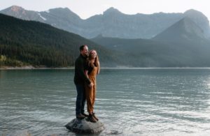 Casual engagement session in Kananaskis, South of canmore, as couple stands laughing on a rock