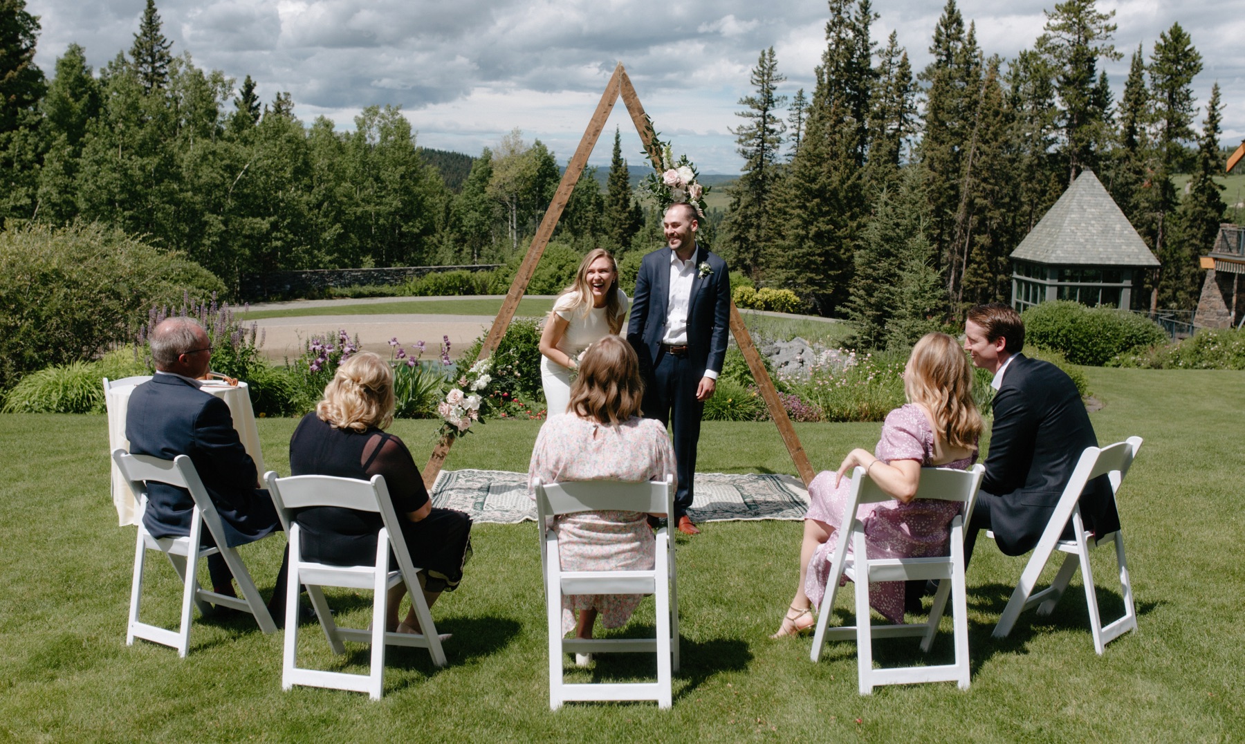 Livestreamed small wedding ceremony at Azuridge Estate with couple laughing under triangle arch