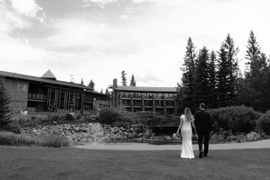 Bride and groom walkign across lawn looking back at Azuridge Estate