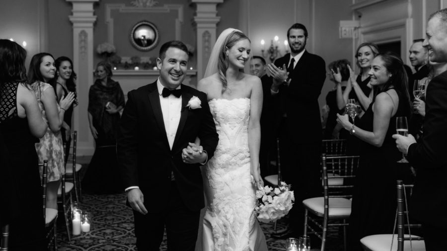 Classic wedding ceremony recessional with bride and groom grinning at clapping guests