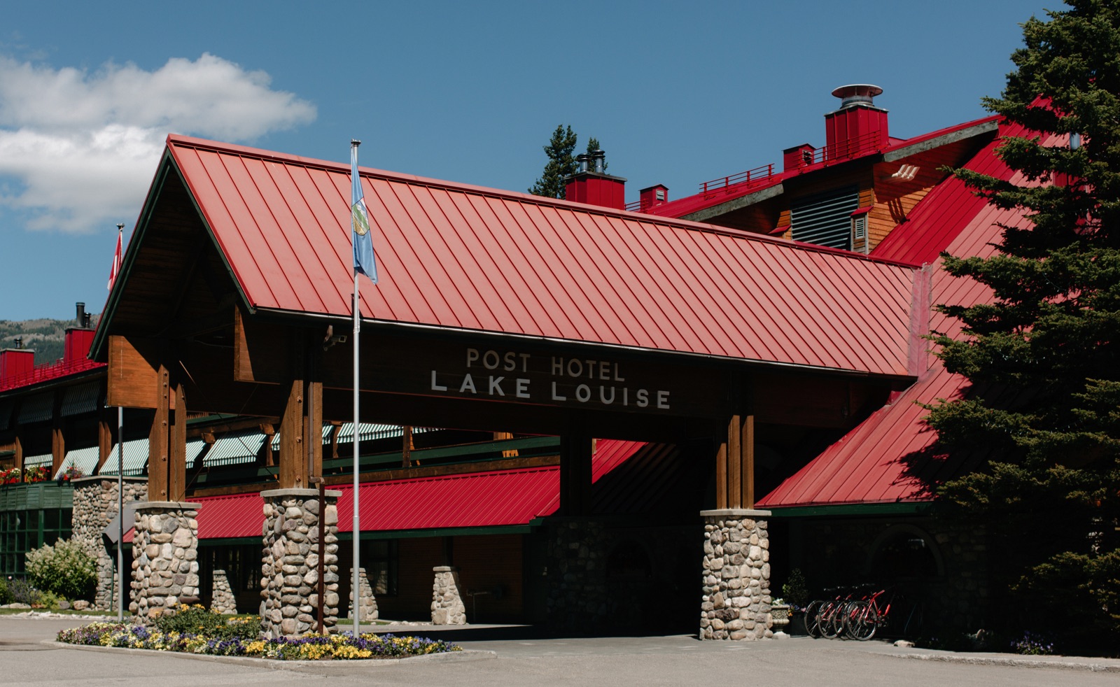 Front entrance exterior of the Post Hotel with a cherry red roof in Banff National Park