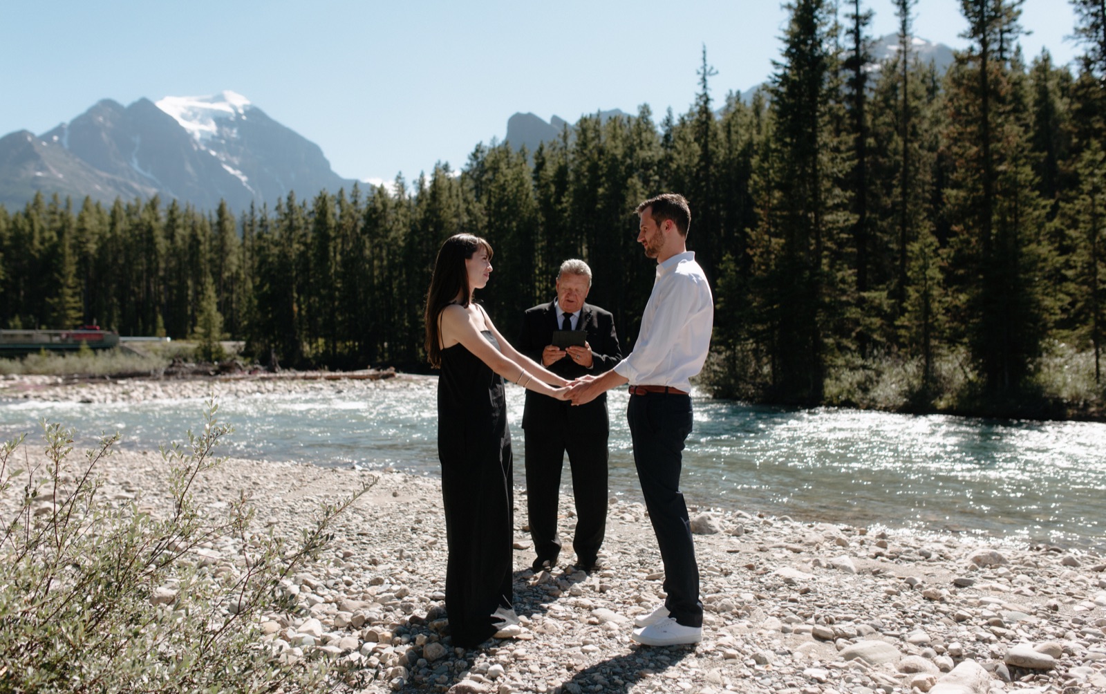 Post Hotel elopement with couple holding hands overlooking Mount Temple and the Bow River in Lake Louise