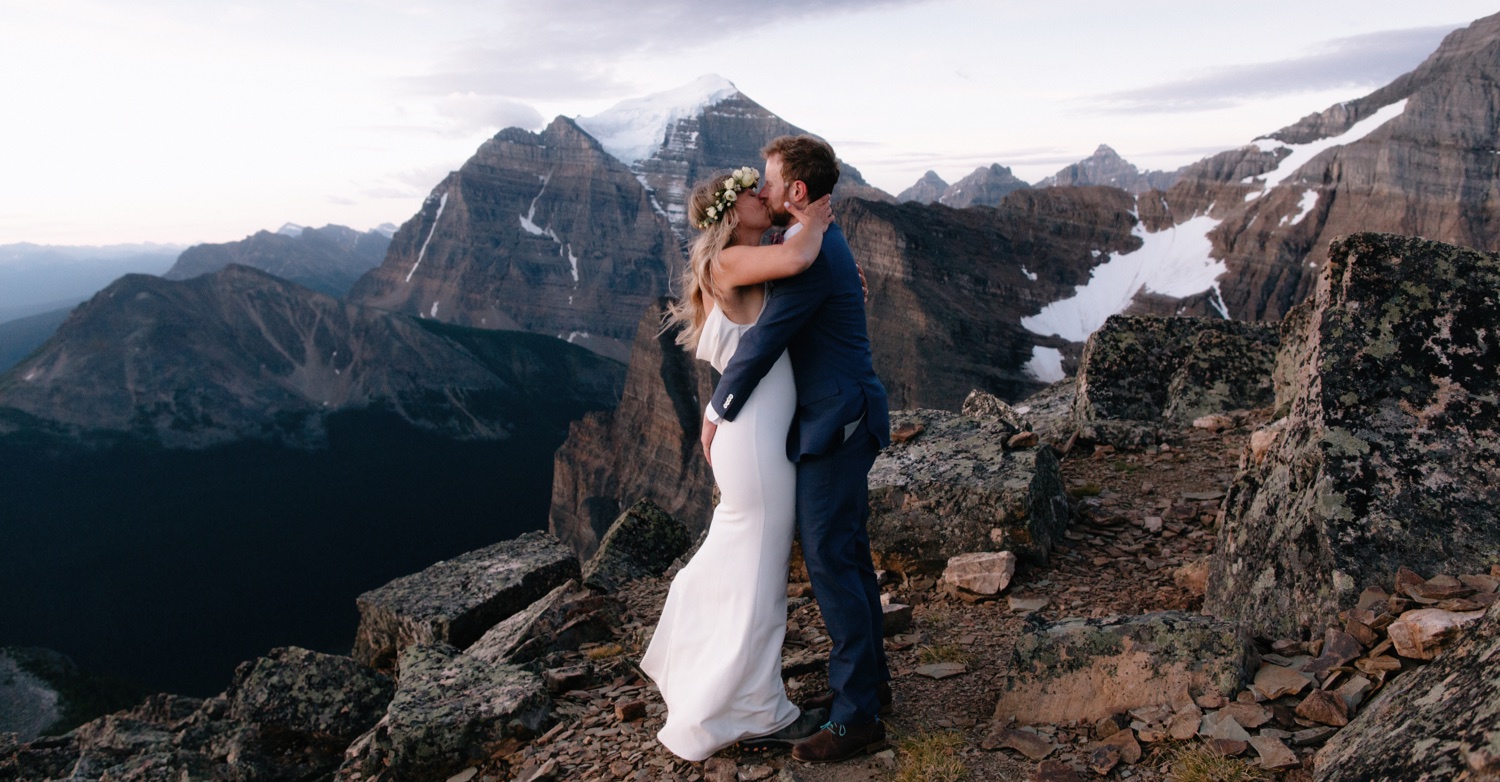 First kiss for a hiking elopement with Mount Temple backdrop over Lake Louise