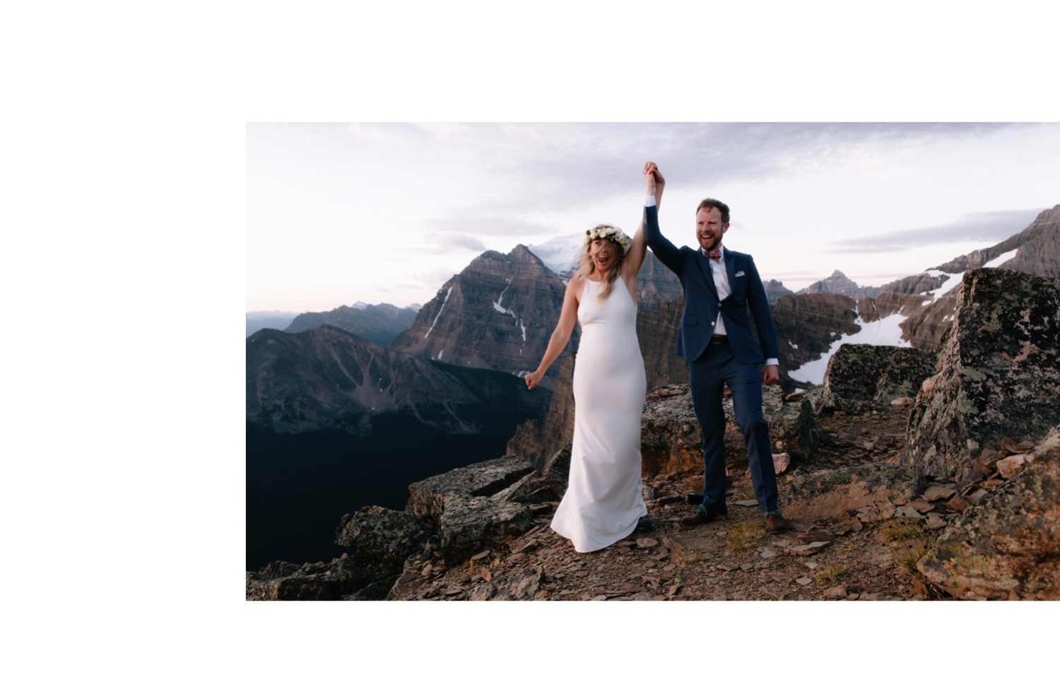 Eloped couple raising arms together in celebration after being announced husband and wife atop Fairview Mountain in Banff