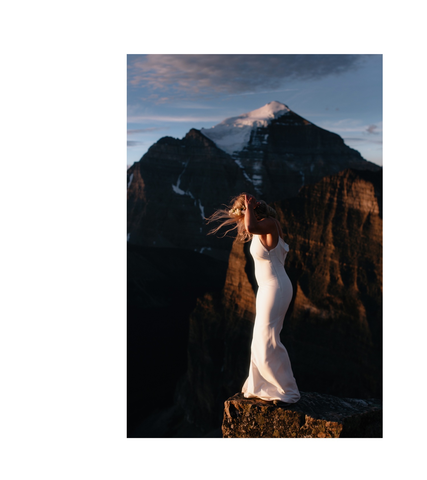 Bride bracing form the wind during a summit summer elopement on Fairview Mountain overlooking Mount Temple