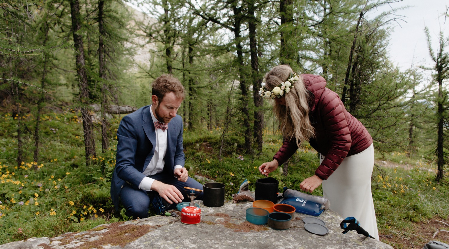 Hiking elopement couple brewing fresh coffee with a camping stove on a lichen covered rock