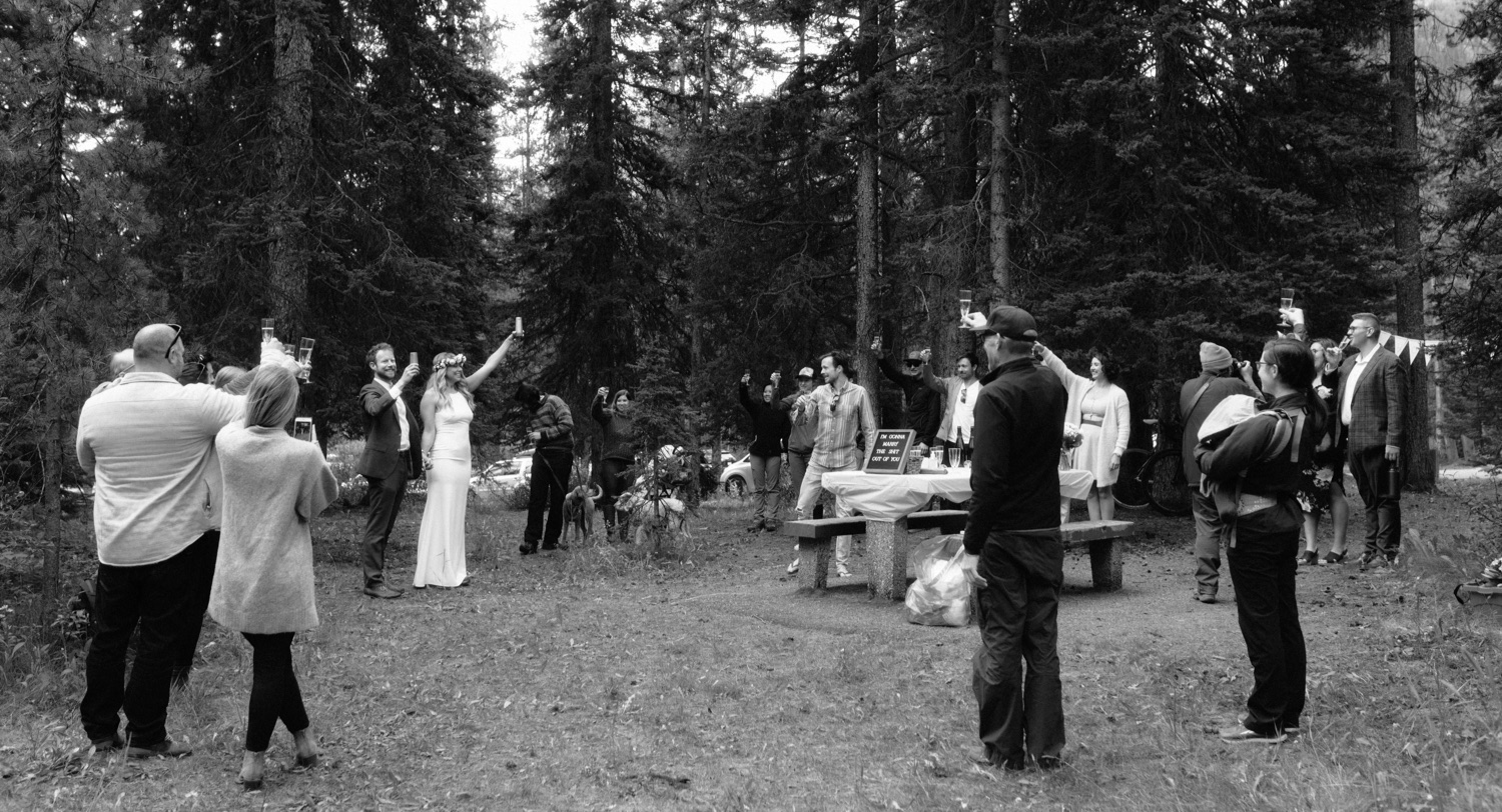 Couple distantly celebrating their hiking elopement at an impromptu reception at a Banff picnic area