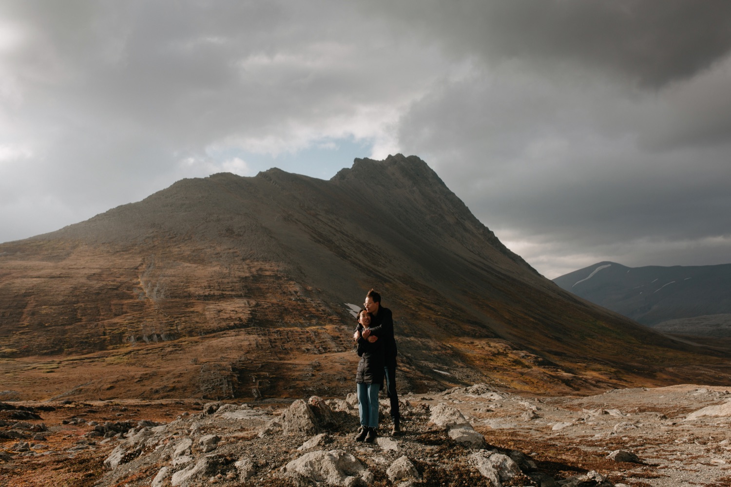 Couple embracing in Canadian Rockies that look more like the Isle of Skye with orange and warm tone foliage