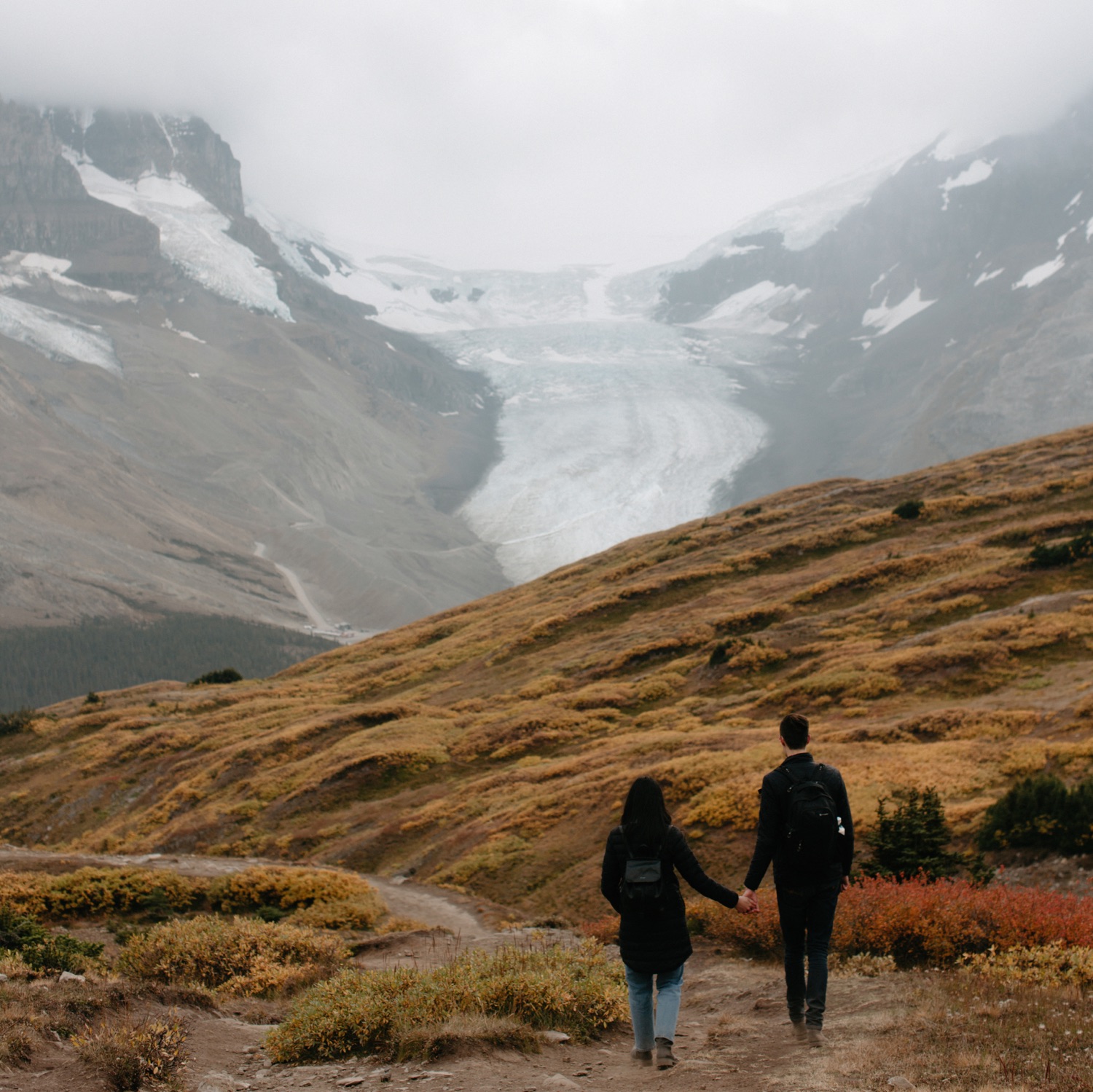 Couple hiking down Wilcox Ridge overlooking the Athabasca Glacier in autumn