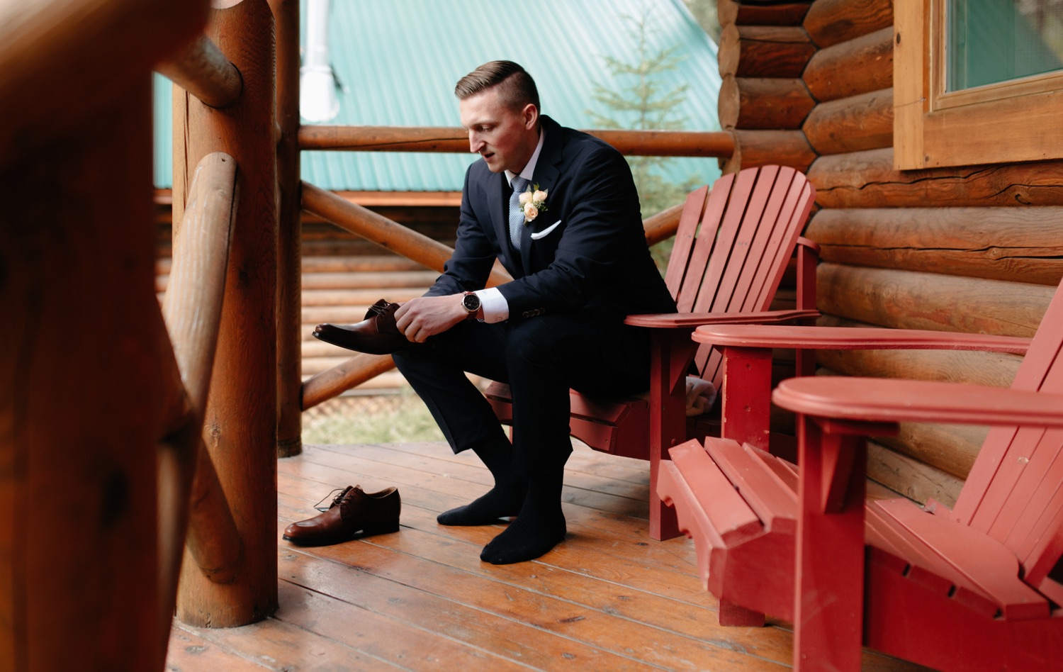 Groom getting ready on the front porch of the historic cabins at Cathedral Mountain Lodge
