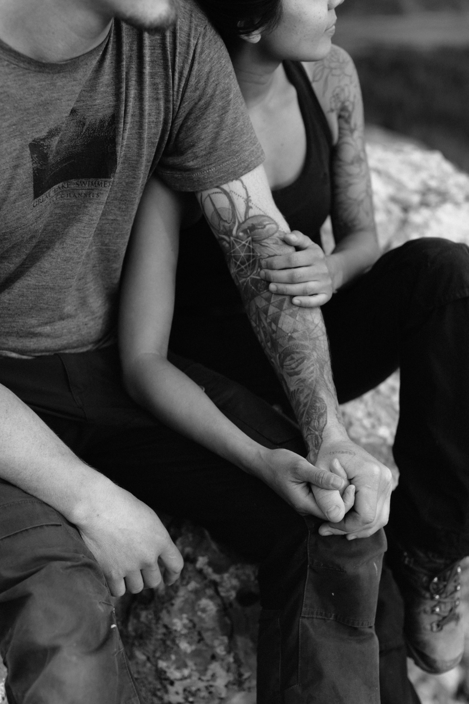 Couple embracing while sitting with interlocking hands with modern tattos