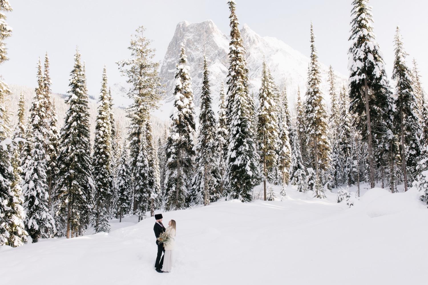 Classic winter wedding portraits with snow covered trees and Mount Burgess in Yoho National Park