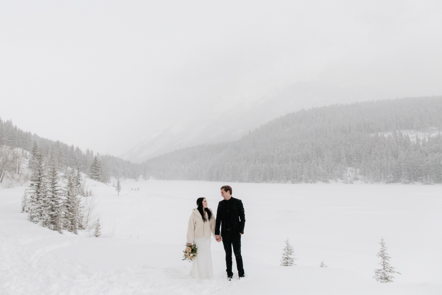 Two Jack Lake winter wedding portraits with soft warm pink and orange bouquet hues from Amborella Florals