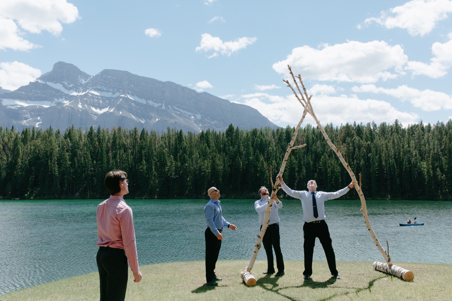 Men holding up birch altar as in front of Johnson lake and Mount Rundle