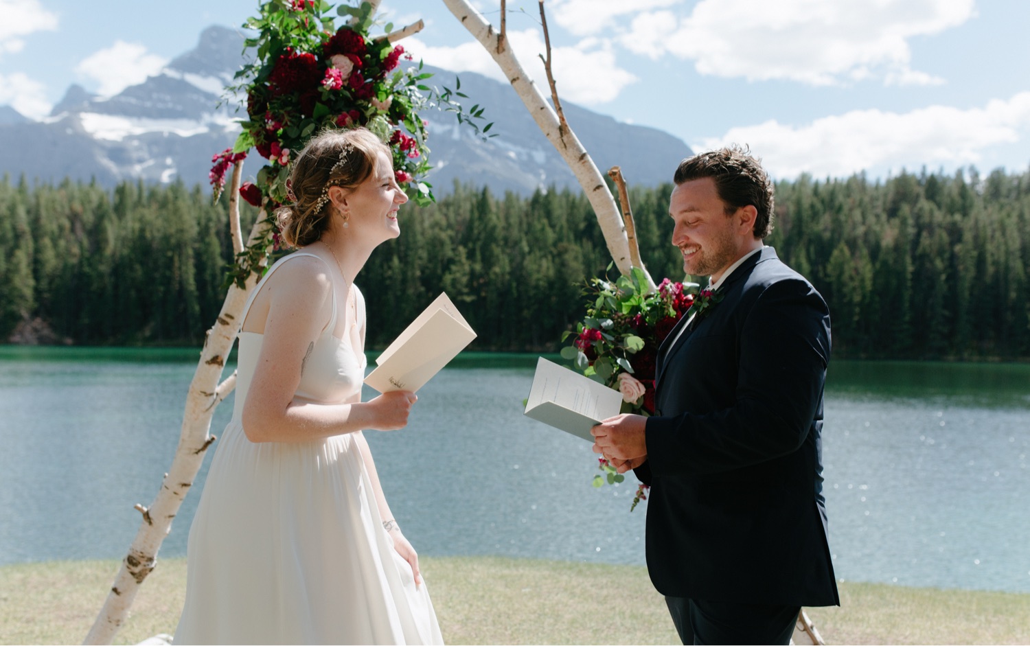 Couple reading custom vows from booklets on a bright summer midday in Banff National Park
