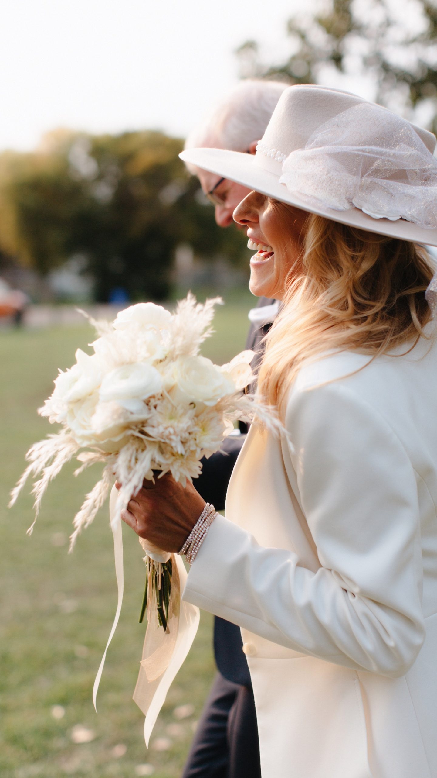 Impeccable mature bride style with pant suit, white bouquet and fascinator hat