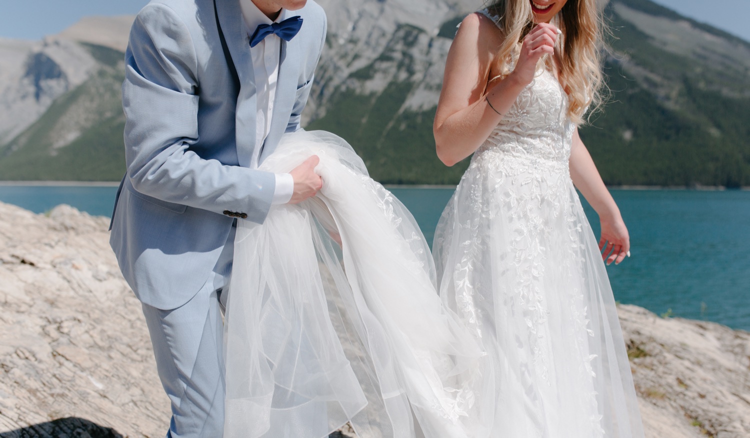 Groom carrying the tulle of the skirt at Lake Minnewanka